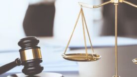 Balanced scale of justice and gavel hammer in focus on blurred background
