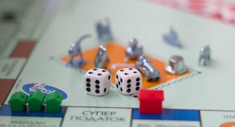 Monopoly board with green and red houses and dice on top