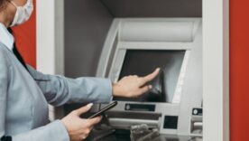 A business woman at an ATM wearing a mask