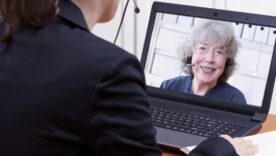 A woman in a suit talking virtually on a computer to another lady on the screen