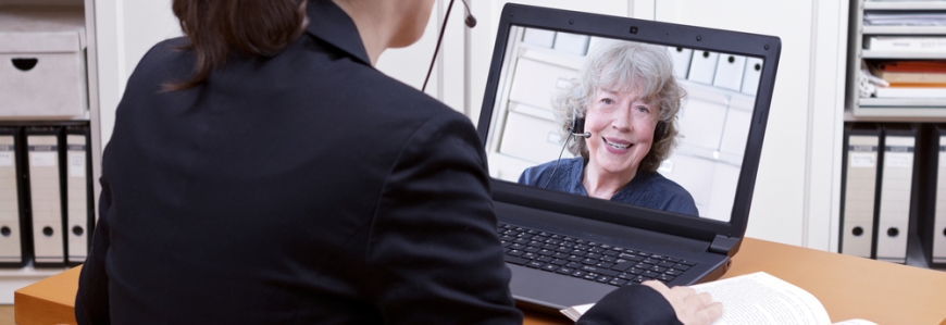 A woman in a suit talking virtually on a computer to another lady on the screen