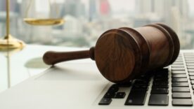 Legal weights in background with a gavel resting on a laptop