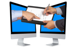 Two desktop screens facing each other with hands coming out of both and signing a document in the middle
