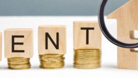 Piles of coins with wooden block on them spelling out the word rent
