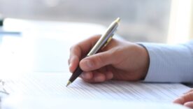 Man in work shirt filling out a questionnaire on a desk