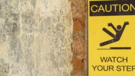Brick wall with a caution watch your step sign on the wall