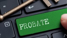 Keyboard with the word PROBATE on one of the keys with a hand pressing it. A led key is in resting on the keyboard.
