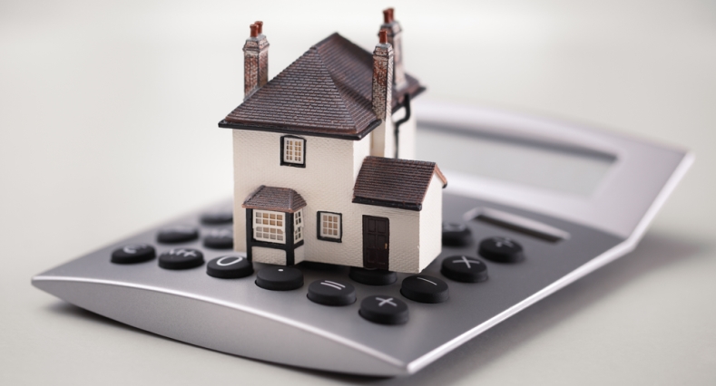 A calculator with a small toy house on top of it