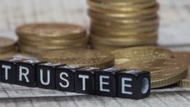 Dice with the name trustee written across in front of gold coins