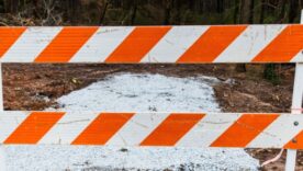 A warning or danger sign blocking off iced ground leading to land with trees in the background