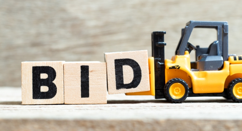 Toy tow truck picking up wooden bricks with the word BID painted on them