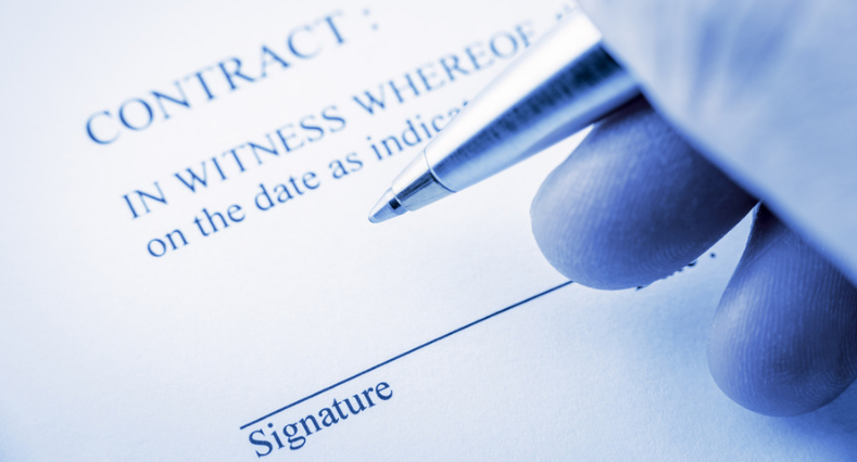 Hand holding a blue ballpoint pen preparing to sign a contract