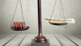 Scales of justice with gavel on one side and a pile of cash notes on the other side