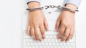 Female hands in handcuffs with laptop