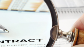 Magnifying glass over papers and word "Contract"in focus
