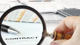 Magnifying Glass Over Papers and Word "Contract" in Focus