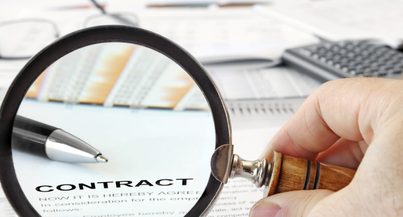 Magnifying Glass Over Papers and Word "Contract" in Focus
