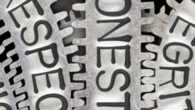 Macro photo of tooth wheel mechanism with ETHICS, RESPECT, HONESTY and INTEGRITY words imprinted on metal surface
