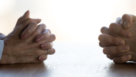 Close up clasped hands of two businesspeople negotiate at table
