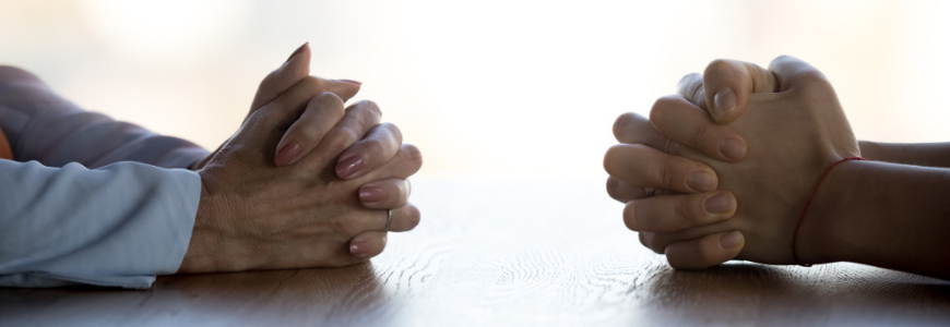 Close up clasped hands of two businesspeople negotiate at table