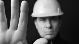 Builder in a hardhat with his hand up to indicate stop