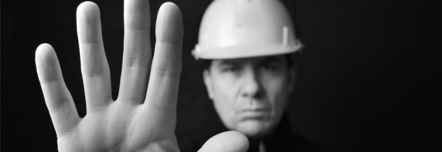 Builder in a hardhat with his hand up to indicate stop
