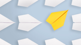 white paper planes all the same direction and one yellow paper plane going in a different direction