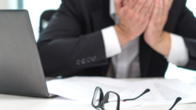 Stressed business man covering face with hands in office.