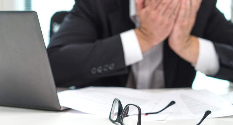Stressed business man covering face with hands in office.