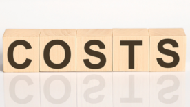COSTS word from wooden blocks on white desk