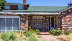 Abandoned Brick Home With Overgrown Front Yard