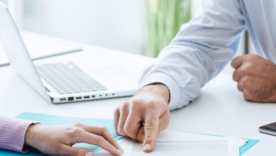 A man explaining terms of a contract to a woman at a desk
