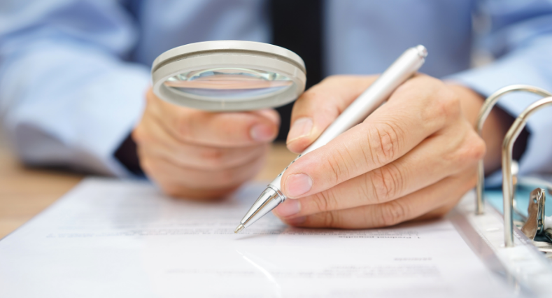 Businessman is analyzing through magnifying glass contract and prices