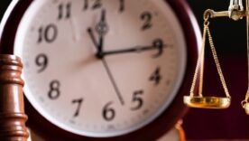 table with judge hammer, balance scale and wall clock