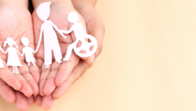 Hands holding paper Cutout of different family members being together.