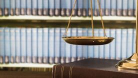 Scales of justice on law books in library of law firm.