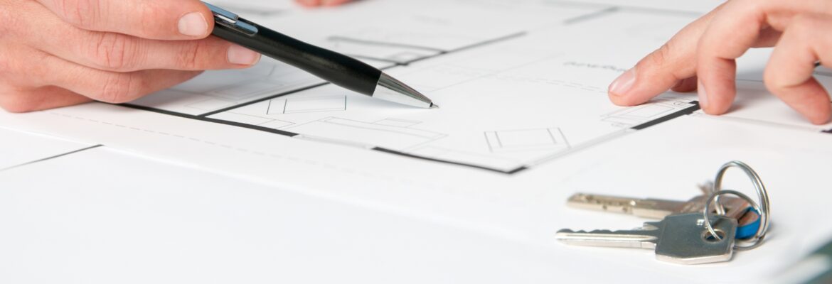 Closeup view of keys and drawing plan during a discussion with a real estate agent
