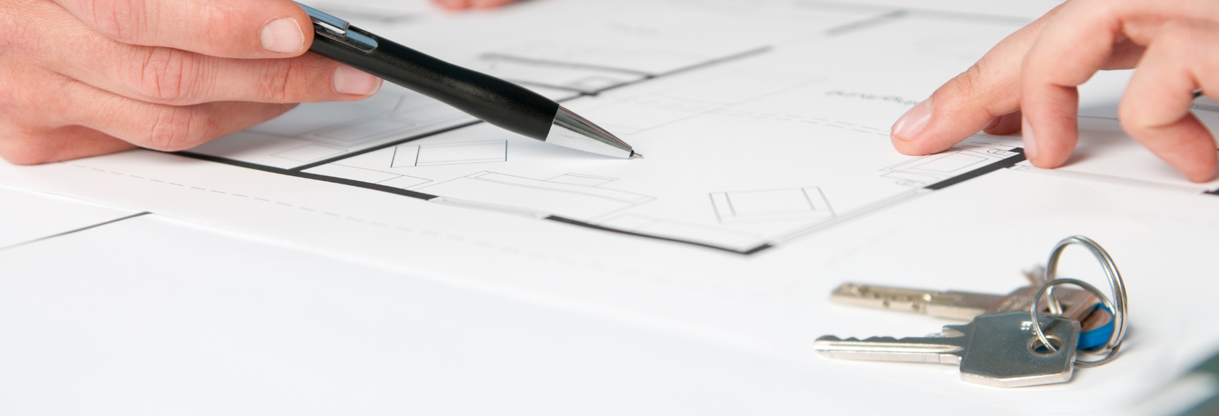 Closeup view of keys and drawing plan during a discussion with a real estate agent