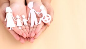 Hands holding paper cutout of different family members being together