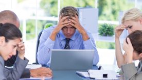 Business team looking down with head in hands looking very upset.