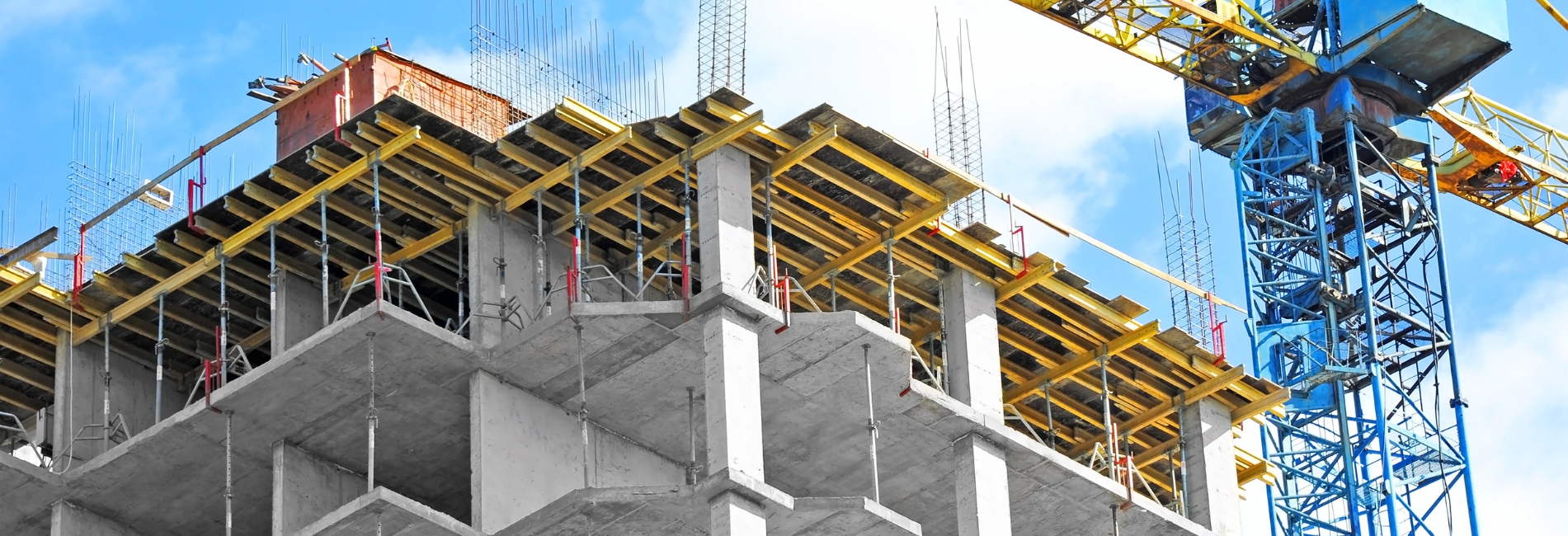 Crane and building under construction against blue sky