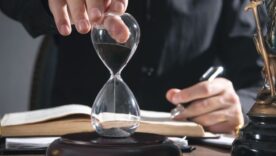 Judge's hand showing hourglass in a courtroom.