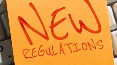 Writing on a post-it note displaying the text "New Regulations"