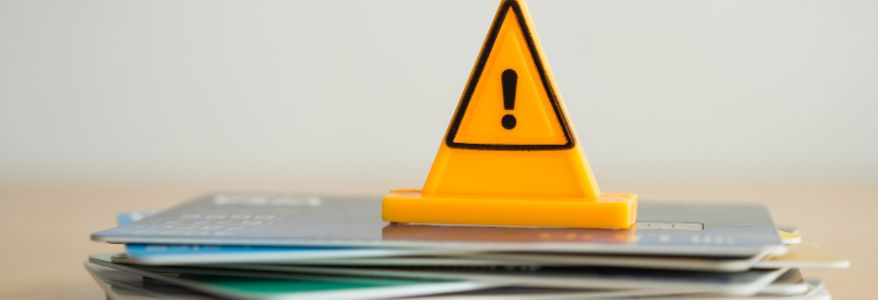 Close up yellow triangle emergency warning sign placed on a stack of credit cards