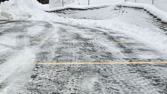 A top down view of a cleared parking lot of snow with lots of ice left behind on it