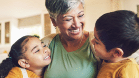 A grandmother and her two grandchildren sitting together and smiling on a couch