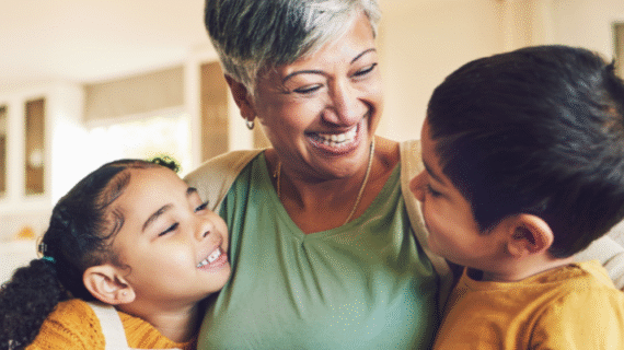 A grandmother and her two grandchildren sitting together and smiling on a couch