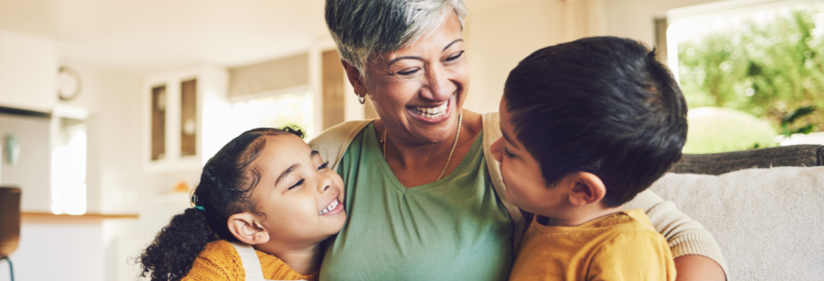 A grandmother and her two grandchildren sitting together and smiling on a couch