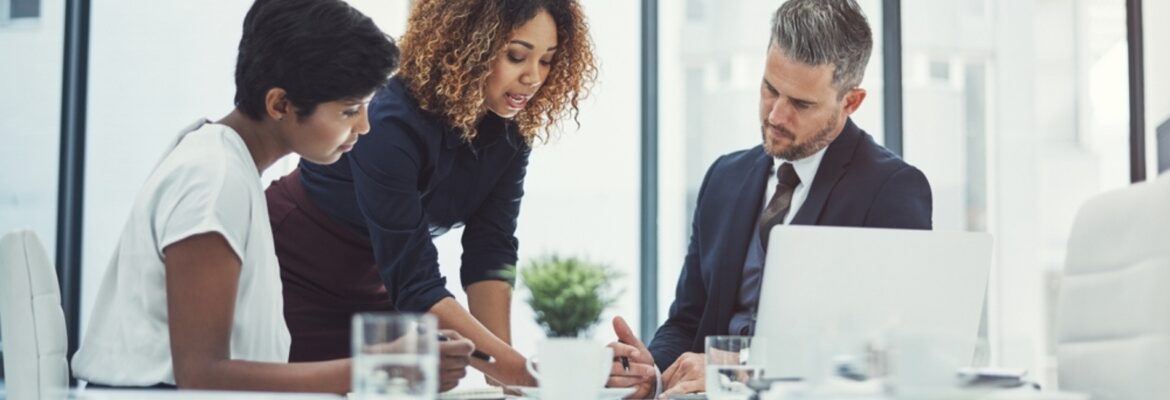 A group of professionals collaborates in a modern office setting, reviewing documents and discussing ideas around a table.