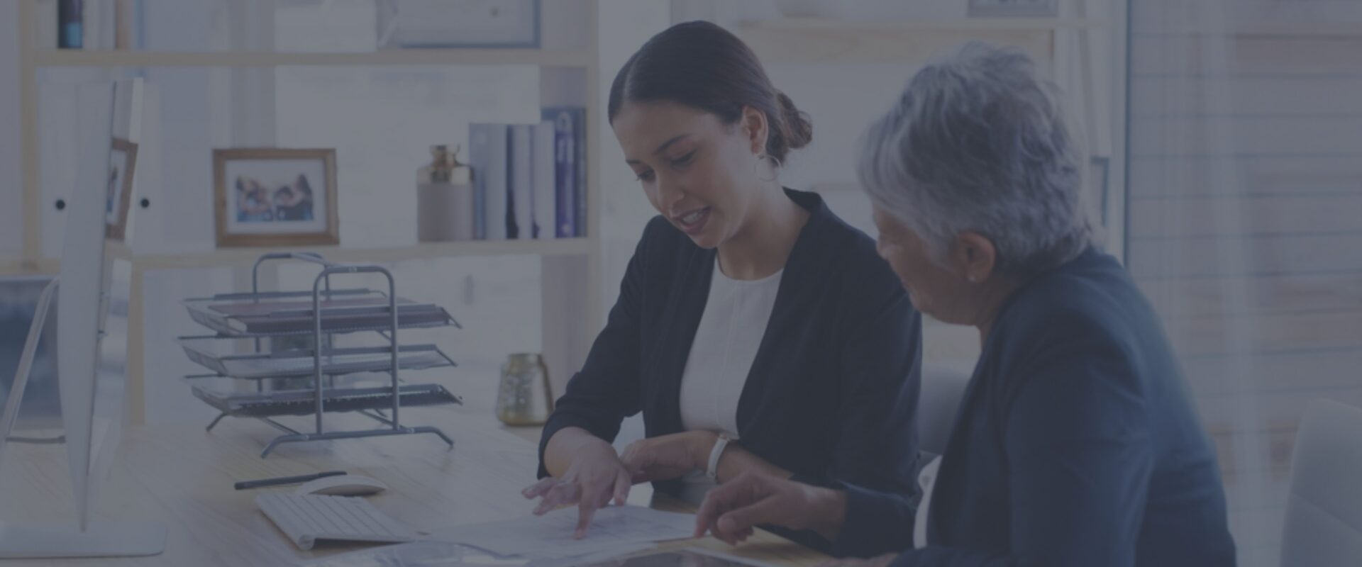 Two women working at a desk looking at a document